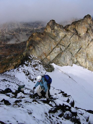 When we reached the col, it was much more snowy on the far side.
We turned and headed up the side of the ridge toward the summit.
Behind Eileen in this picture, the east side of Cardinal's north peak was a dramatic wall of white rock.